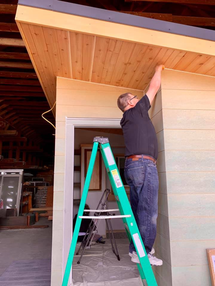 Man Standing on Ladder to work on Roof of home
